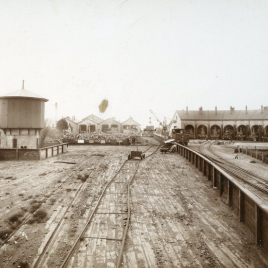 Rundremise med plads til 8 lokomotiver med tilhørende drejeskive ses til højre i billedet. I baggrunden midt i billedet ses værkstedsbygningerne, hvoraf en del stadig er bevaret og taget i brug af Nyborg Destilleri. Tårnet til venstre i billedet er et vandtårn, hvorfra damplokomotiverne påfyldtes det nødvendige vand til dampproduktion. 1890.