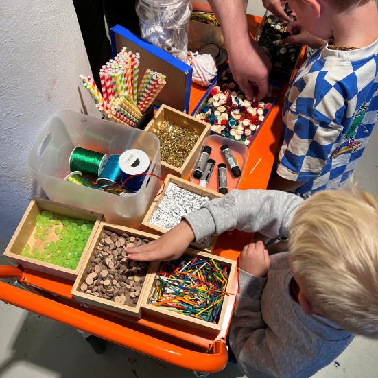 Børn står og vælger materialer til deres kæphest.