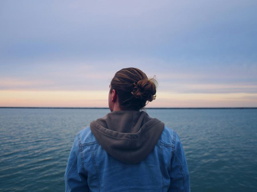 Mand står og kigger ud over havet.