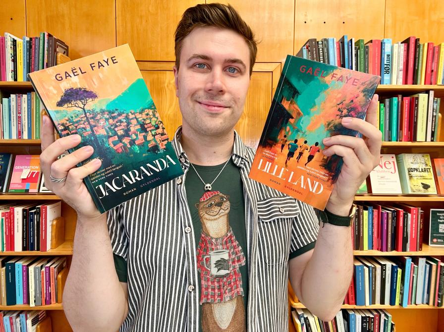 Bibliotekar Mathias står med bogforsiderne til "Lille land" og "Jacaranda"